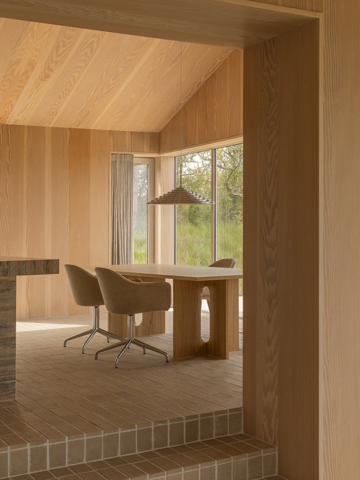 A wood-panelled dining room featuring an Androgyne Dining Table, Harbour Swivel Chairs, and a Chancery Pendant Lamp.
