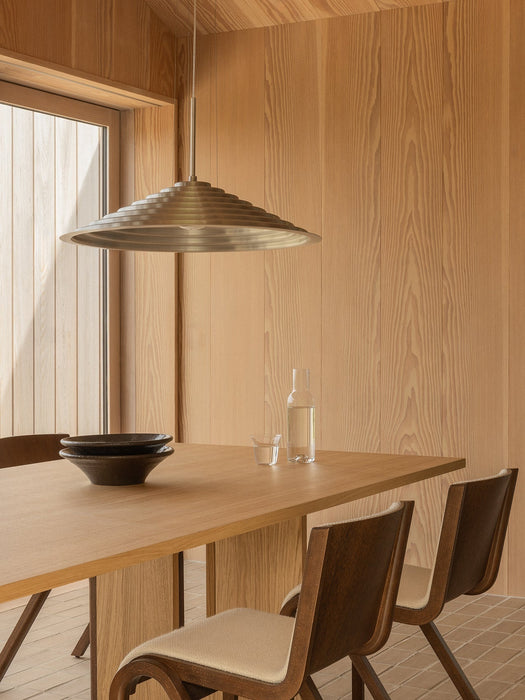 The Chancery Pendant Lamp hangs over an Androgyne Dining Table with Ready Chairs, a Triptych Bowl, and Bottle Carafe.
