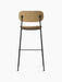 Rear view of the Co Bar Chair in light brown bouclé fabric. The chair has a slender, tubular black steel frame and footrest.