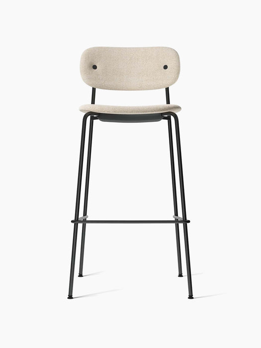 Front view of the Co Bar Chair with a black steel frame, footrest, and light Moss fabric upholstery on its seat and back.