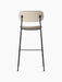 Rear view of the Co Bar Chair, Fully Upholstered, with light beige fabric seat and back on a slender black steel frame.