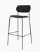The Co Bar Chair, Fully Upholstered, has a slim black steel frame with a footrest, and dark seat and backrest.