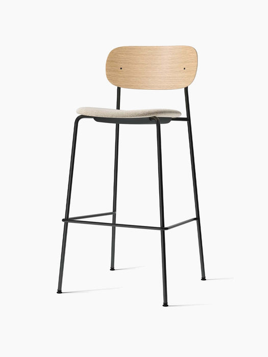 Front-angle view of the Co Bar Chair with natural oak backrest, light grey upholstered seat, and black steel frame.