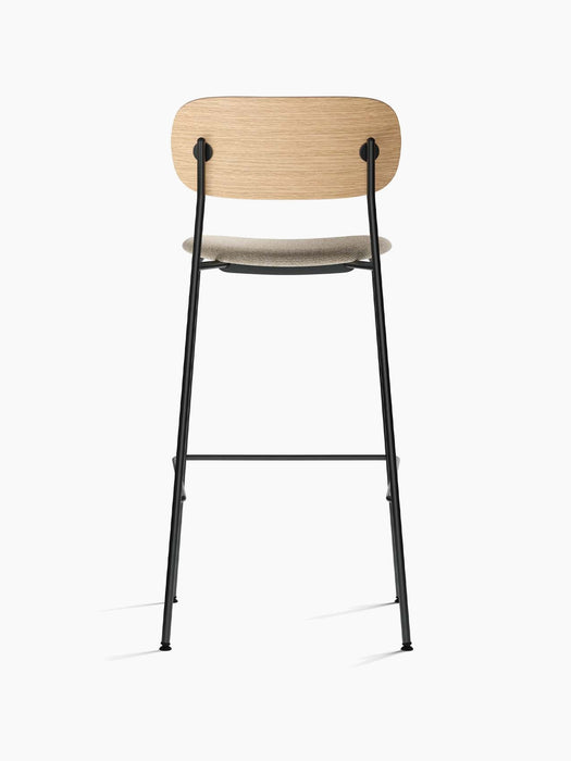 Back view of the Co Bar Chair with an upholstered moss fabric seat, natural oak backrest, and slender black steel frame.