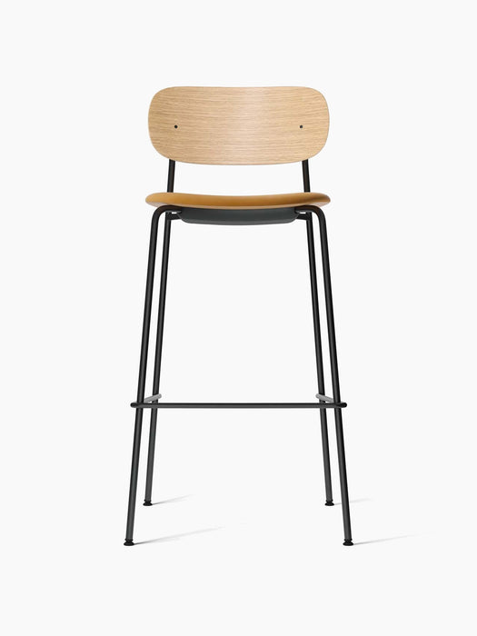 Front view of the Co Bar Chair with a natural oak backrest, a dark upholstered seat, and a slender black tubular steel frame.
