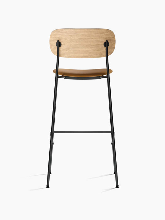 Back view of the Co Bar Chair, upholstered seat in light brown leather, a natural oak backrest, and a black steel frame.