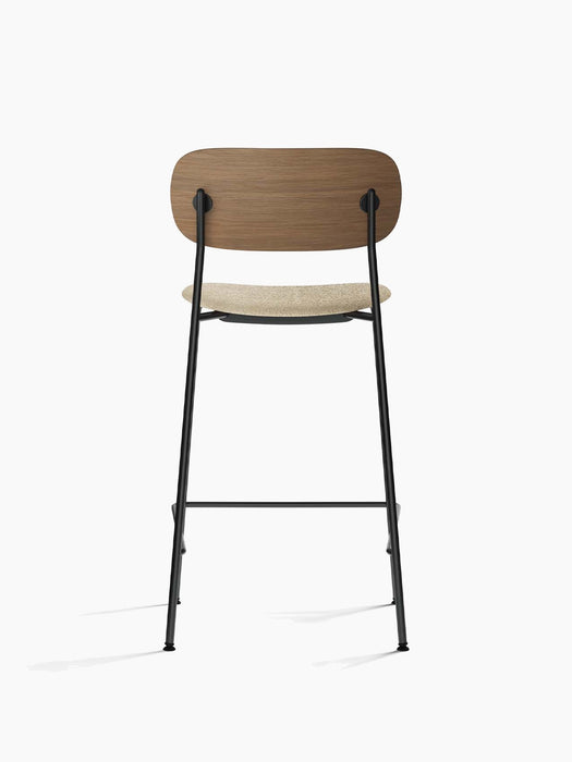 Back view of the Co Counter Chair with a dark stained oak backrest, bouclé upholstered seat, and a slender black steel frame.