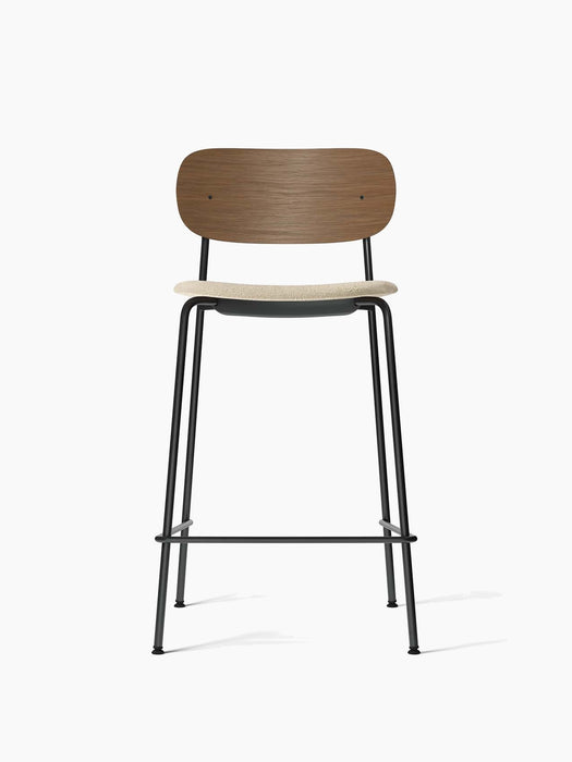 Front view of the Co Bar Chair with a dark stained oak backrest, cream bouclé upholstered seat, and a black steel frame.