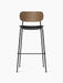 Front view of the Co Bar Chair with a dark stained oak backrest, black upholstered seat, and slender black steel frame.