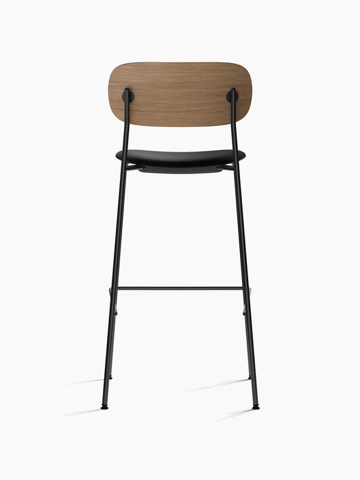Back view of the Co Bar Chair with a dark stained oak backrest, a black upholstered seat, and a slender black steel frame.