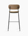 Back view of the Co Bar Chair with an upholstered seat, featuring a dark stained oak backrest and a slender black steel frame