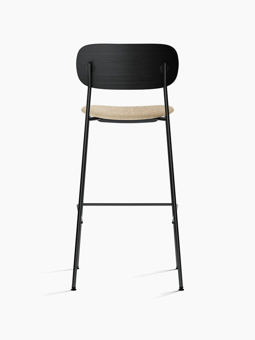 Back view of the Co Bar Chair, Seat Upholstered, with a black oak backrest, beige bouclé seat and slim black steel frame.