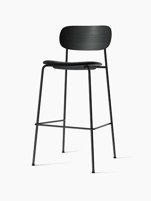 Angled view of the Co Bar Chair, Seat Upholstered, with a black oak backrest, upholstered seat, and black steel frame.