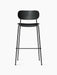 Front view of the Co Bar Chair with a black oak backrest, dark upholstered seat, and slender black steel frame with footrest.