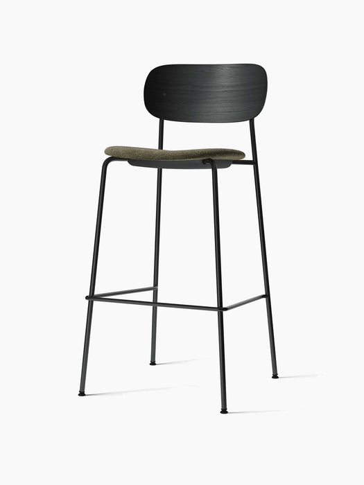 A Co Bar Chair with a black oak backrest and a moss green upholstered seat, set on a slender black steel frame.