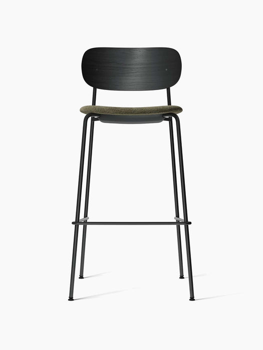 Co Bar Chair, viewed from the front, with a black steel frame, a black oak wood backrest, and a moss green upholstered seat.