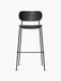 Co Bar Chair, viewed from the front, with a black steel frame, a black oak wood backrest, and a moss green upholstered seat.