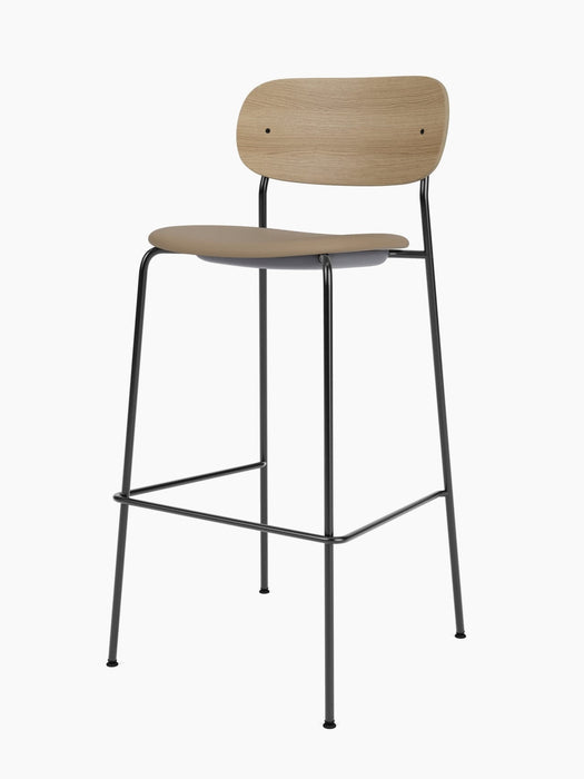 Co Bar Chair, Seat Upholstered, from an angle. Black steel frame, light brown seat, and natural oak backrest.