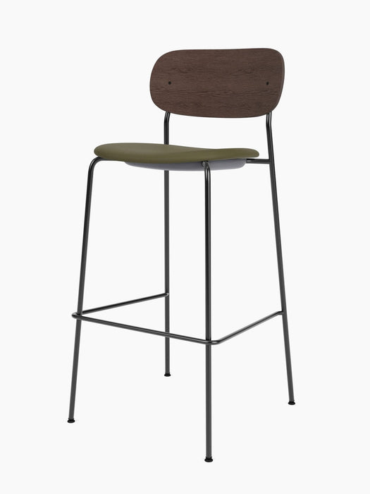 Angled view of the Co Bar Chair with upholstered seat, dark stained oak back, olive green seat and slim black metal frame.