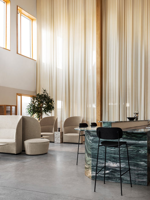 Black Co Bar Chair at a green marble island. In the background, Tearoom Sofa, Lounge Chairs, and Cairn Pouf seating area.