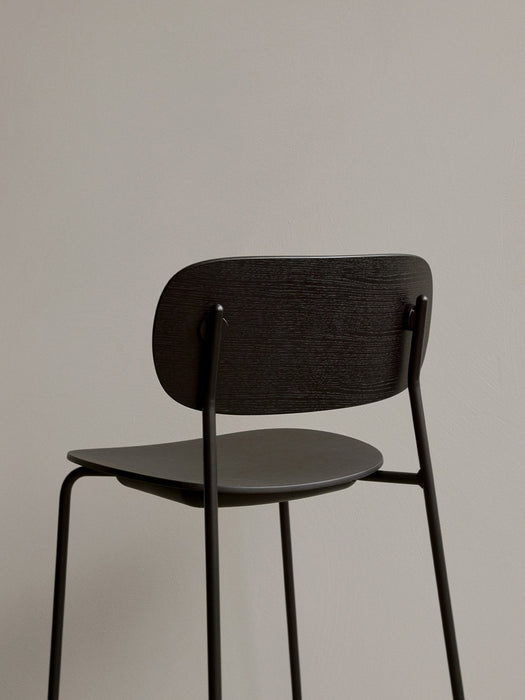 Rear close-up of the Co Bar Chair in dark stained oak veneer, focusing on the textured backrest and slim black metal frame.