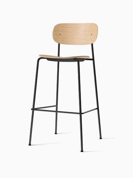 The Co Bar Chair, Veneer in natural oak, shown at an angle, with a curved seat and backrest on a slender black steel frame.