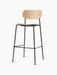 The Co Bar Chair, Veneer in natural oak, shown at an angle, with a curved seat and backrest on a slender black steel frame.