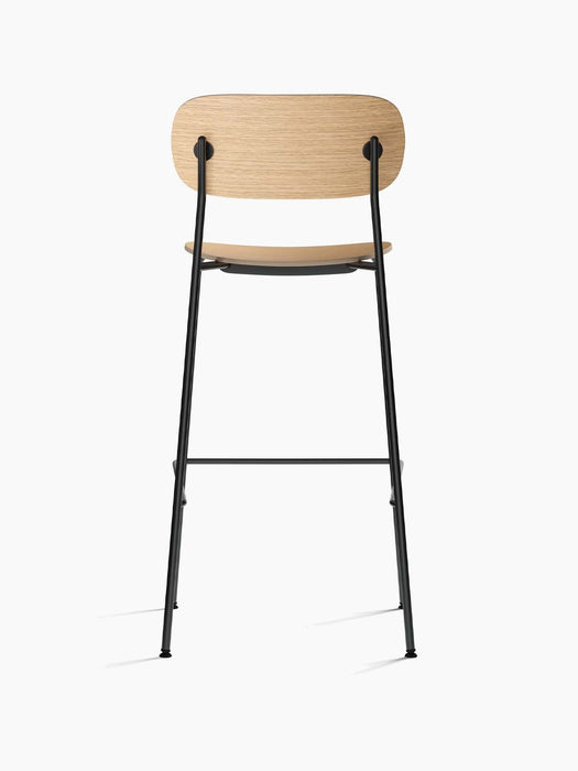 Back view of the Co Bar Chair with a natural oak veneer seat and backrest, supported by a slender black steel frame.