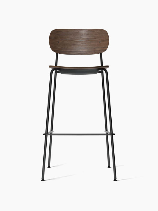 A front view of the Co Bar Chair, featuring a dark stained oak veneer backrest and a slender black powder-coated steel frame.