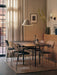 A dining setting featuring Co Dining Chairs in different finishes around a black table by a large window with sheer curtains.