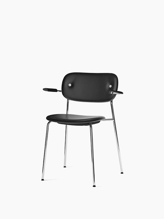 The Co Dining Chair, shown at an angle, with black Dakar leather upholstery, black oak armrests and a slim chrome frame.