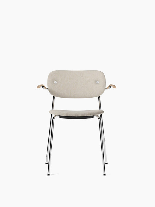 Front view of the Co Dining Chair, fully upholstered in light beige fabric, with natural oak armrests and a chrome frame.