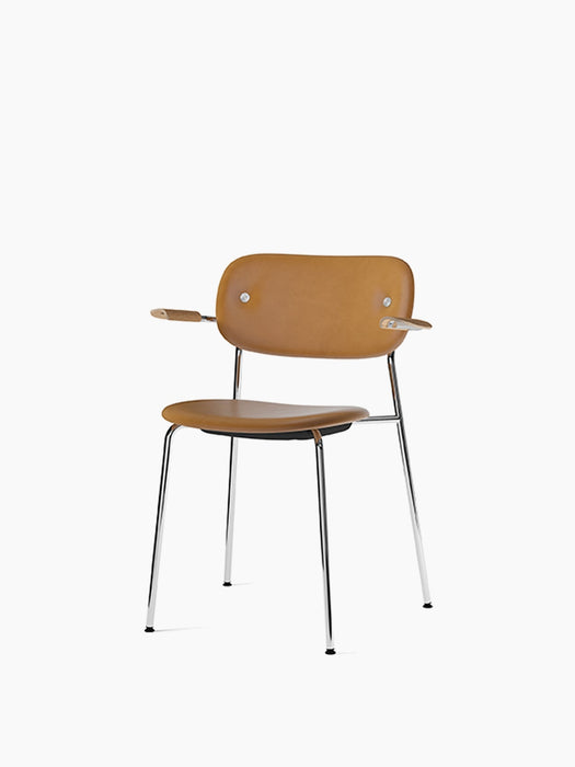 Co Dining Chair, fully upholstered in tan leather with natural oak armrests and a slim chrome frame, on a white background.