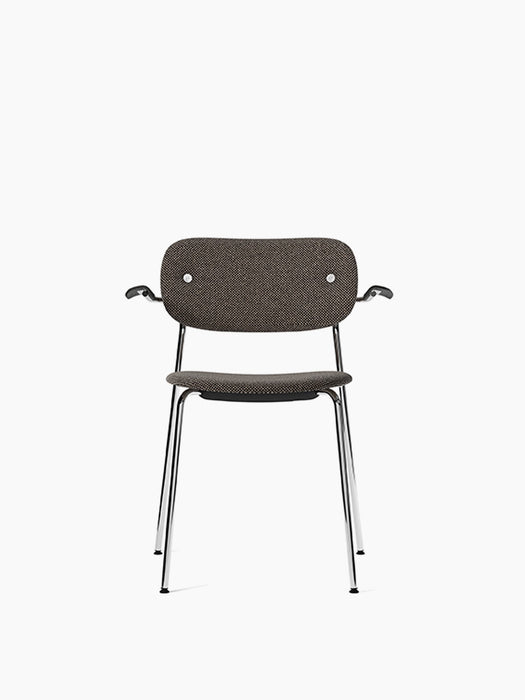 Front view of the Co Dining Chair, fully upholstered in dark textured fabric with black oak armrests and a chrome frame.