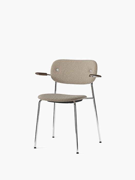 Co Dining Chair with sand upholstery, dark stained oak armrests, and a chrome frame, shown from a slight angle.