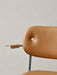 Close-up detail of the fully upholstered Co Dining Chair with armrest, tan leather back, wood armrest, and chrome frame.