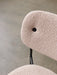 High-angle close-up of the Co Dining Chair, focusing on the textured, light-coloured bouclé upholstery of the backrest.