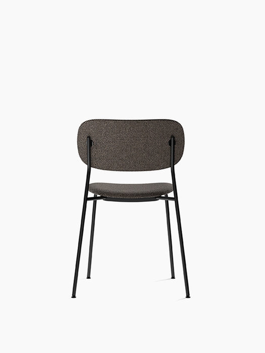 A back view of the Co Dining Chair. It is fully upholstered in a dark, textured fabric and has a slim, black metal frame.