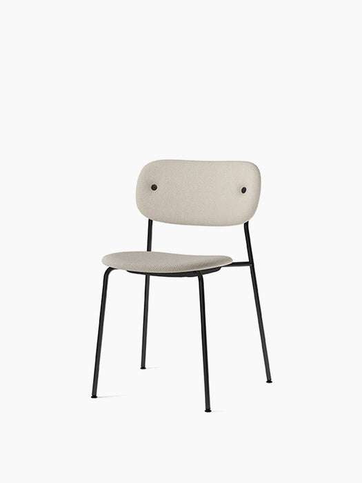 Co Dining Chair, fully upholstered in a light beige textured fabric with a slim black frame, shown at a three-quarter angle