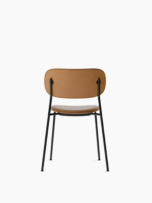Back view of the Co Dining Chair, fully upholstered in tan Dakar leather with a slender, black powder-coated steel frame.