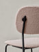 A close-up of the back of the Co Dining Chair, featuring textured, light pink bouclé upholstery and black metal frame.