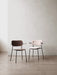 Two versions of the Co Dining Chair with armrests. One in dark stained oak and the other upholstered in a light pink fabric.
