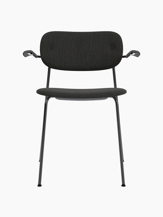 A front view of the Co Dining Chair, fully upholstered with armrests in black. The chair features a slim black metal frame.