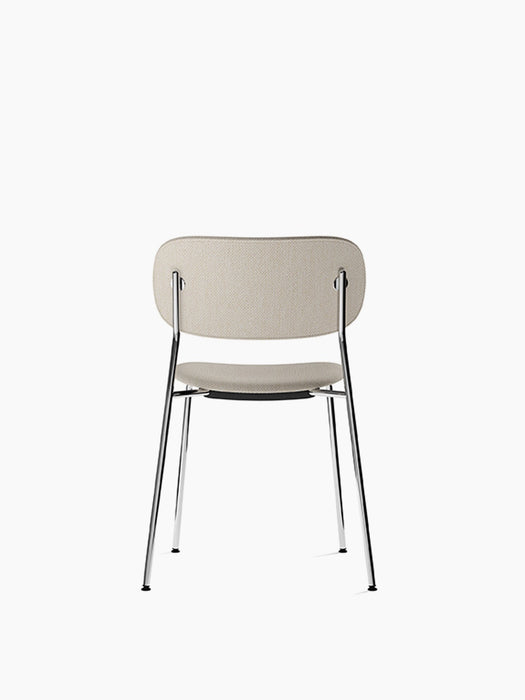 Back view of the Co Dining Chair, fully upholstered in a light beige fabric with a sleek, minimalist chrome frame.