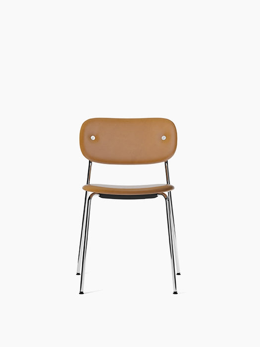 Front view of the Co Dining Chair, fully upholstered in light brown Dakar leather, with a sleek chrome frame and legs.