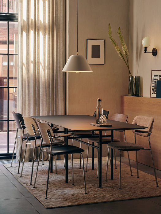 A dining room featuring several Co Dining Chairs with upholstered seats and chrome armrests around a dark rectangular table.