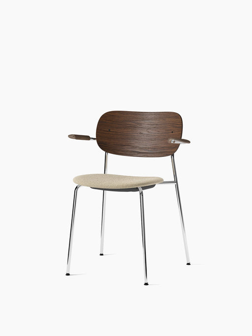 Co Dining Chair with armrests, a dark stained oak backrest, cream bouclé upholstered seat, and polished chrome frame.