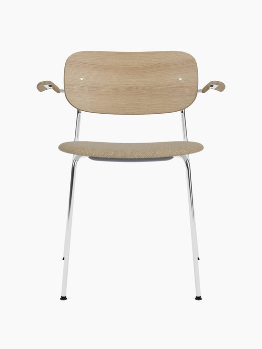 Front view of the Co Dining Chair. It has a natural oak backrest with armrests, a beige upholstered seat, and a chrome frame.