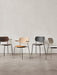 A lineup of four Co Dining Chairs in various finishes and upholstery options, both with and without armrests, against a wall.