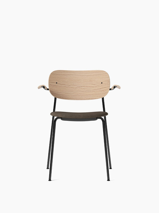 Front view of the Co Dining Chair with a black frame, natural oak backrest and armrests, and a dark, upholstered seat.